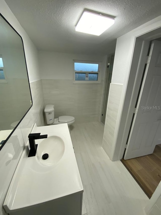 bathroom featuring toilet, hardwood / wood-style floors, vanity, and tile walls