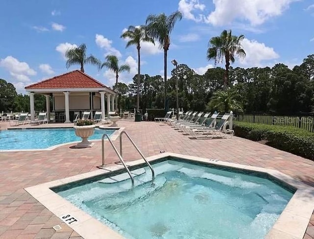 pool featuring a patio, a community hot tub, and fence