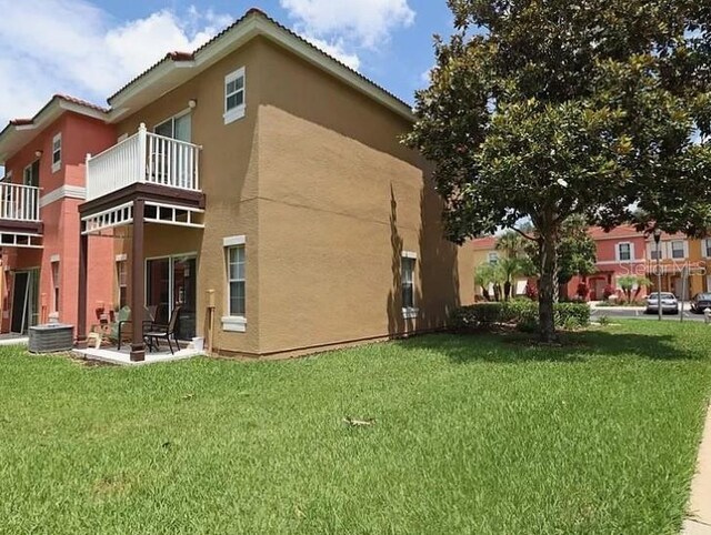 back of property with a balcony, a lawn, and central AC unit