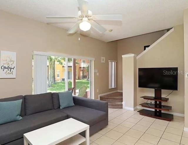 living room with lofted ceiling, ceiling fan, baseboards, and light tile patterned floors