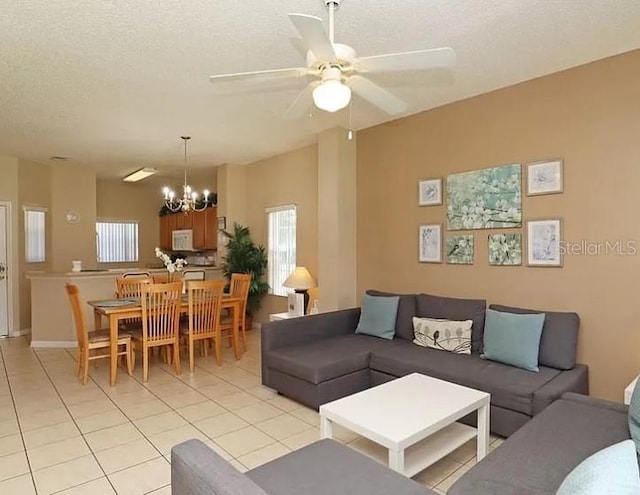 living area featuring ceiling fan with notable chandelier, a textured ceiling, and light tile patterned floors