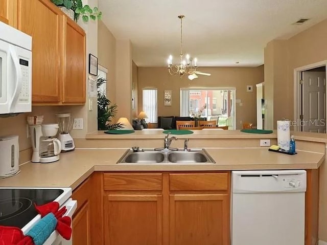 kitchen with a notable chandelier, light countertops, open floor plan, a sink, and white appliances