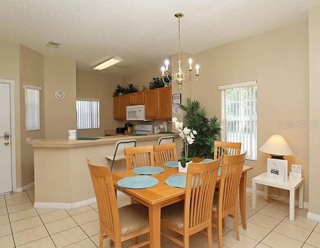 dining room with light tile patterned flooring, a notable chandelier, a textured ceiling, and baseboards