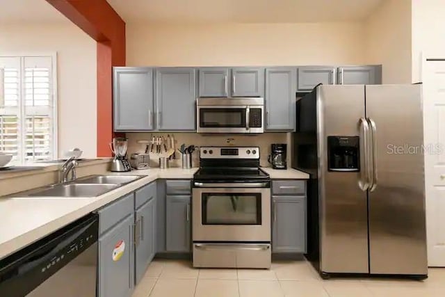 kitchen with appliances with stainless steel finishes, gray cabinetry, and sink