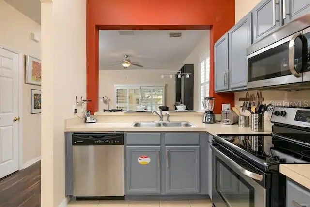 kitchen featuring ceiling fan, appliances with stainless steel finishes, sink, light hardwood / wood-style flooring, and gray cabinets