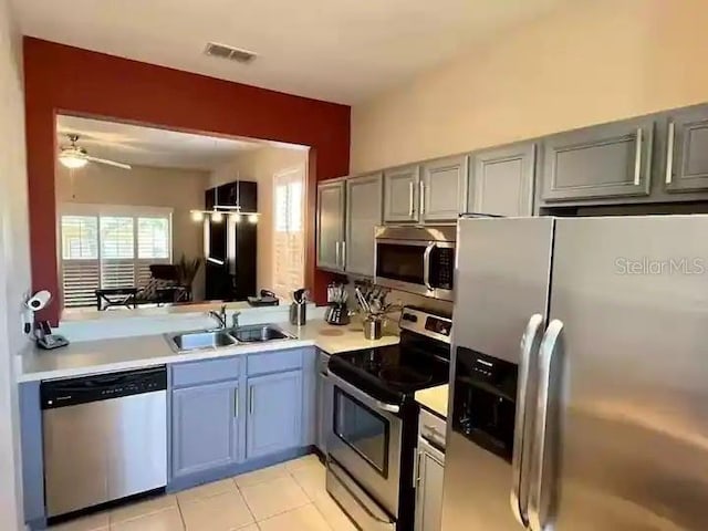 kitchen with gray cabinetry, ceiling fan, sink, stainless steel appliances, and light tile floors