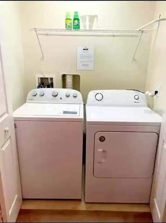 clothes washing area with washing machine and dryer, light hardwood / wood-style floors, and hookup for a washing machine