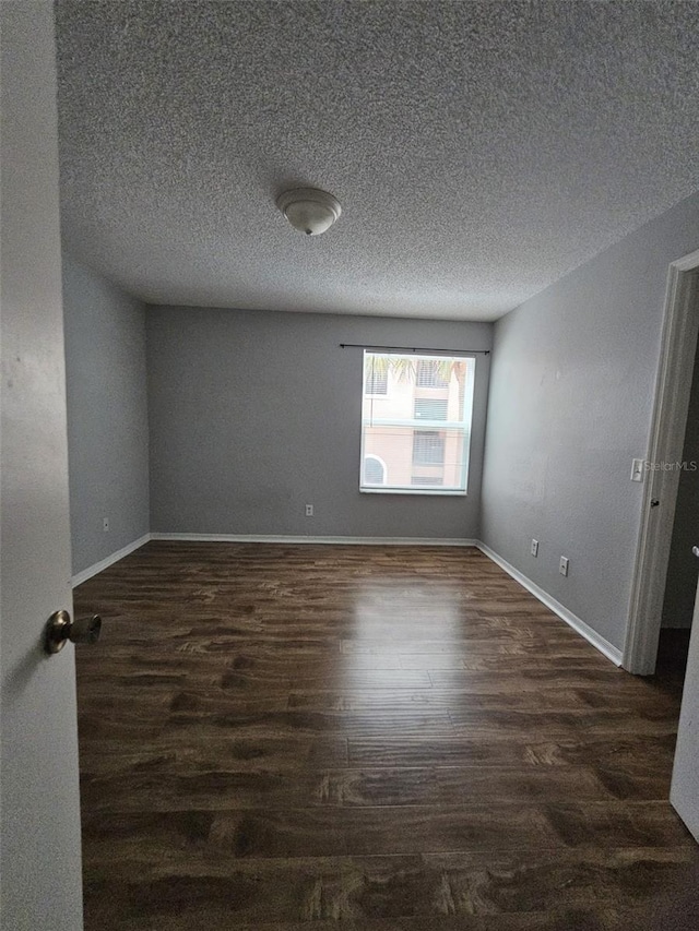 empty room featuring dark wood-type flooring and a textured ceiling