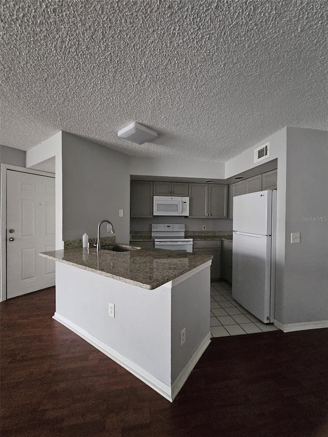 kitchen featuring gray cabinets, hardwood / wood-style floors, sink, dark stone counters, and white appliances