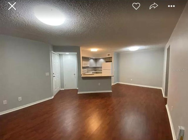 unfurnished living room with dark wood-type flooring and a textured ceiling