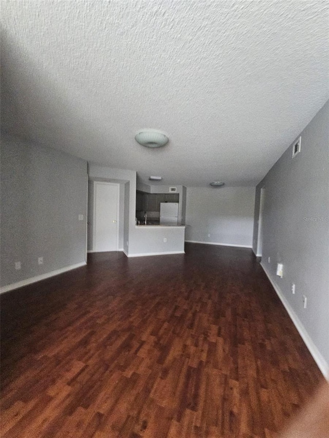 unfurnished living room featuring dark hardwood / wood-style floors and a textured ceiling