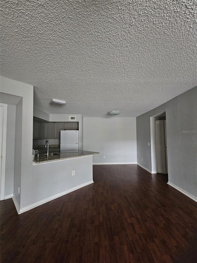 unfurnished living room with sink, a textured ceiling, and dark hardwood / wood-style flooring