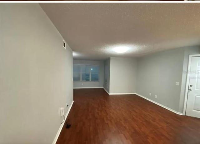 empty room featuring dark hardwood / wood-style floors and a textured ceiling