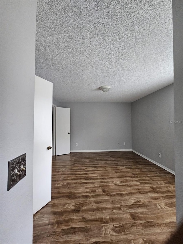 empty room with dark hardwood / wood-style floors and a textured ceiling