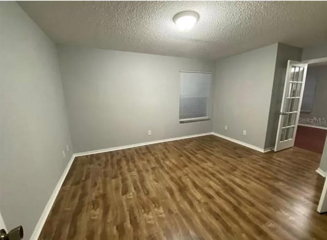 empty room with dark hardwood / wood-style floors and a textured ceiling