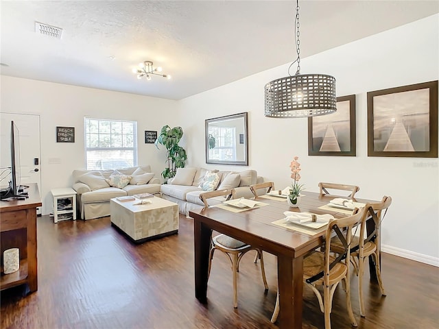 dining room with dark wood-type flooring and an inviting chandelier