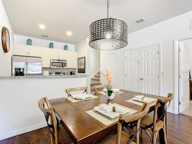 dining area with dark hardwood / wood-style floors and an inviting chandelier