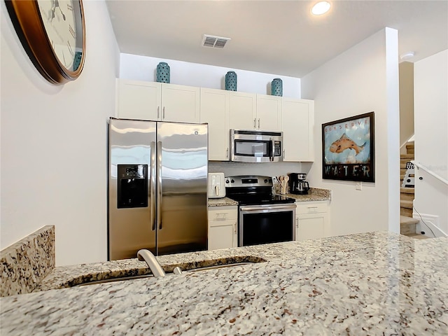 kitchen with white cabinets, light stone countertops, and stainless steel appliances