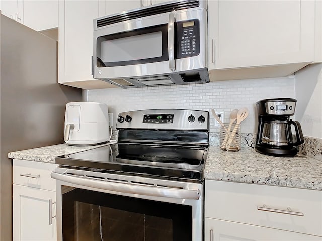 kitchen with white cabinets, backsplash, stainless steel appliances, and light stone counters