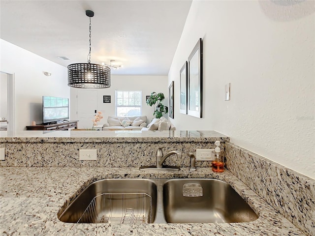 kitchen featuring pendant lighting, sink, and light stone counters