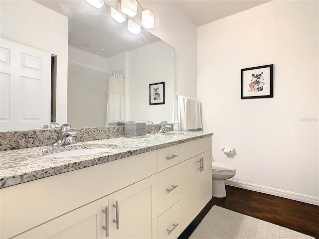 bathroom with dual vanity, toilet, and hardwood / wood-style flooring