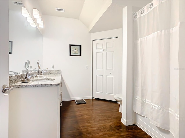 bathroom with vaulted ceiling, oversized vanity, wood-type flooring, and toilet