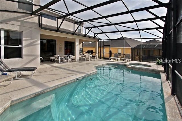 view of swimming pool with glass enclosure, a patio area, and an in ground hot tub