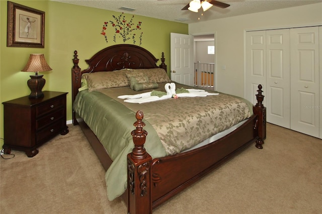 carpeted bedroom with ceiling fan, a textured ceiling, and a closet