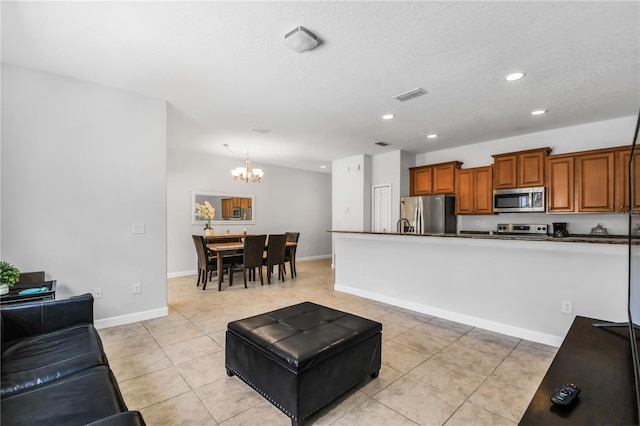 kitchen with an inviting chandelier, light tile floors, decorative light fixtures, and appliances with stainless steel finishes