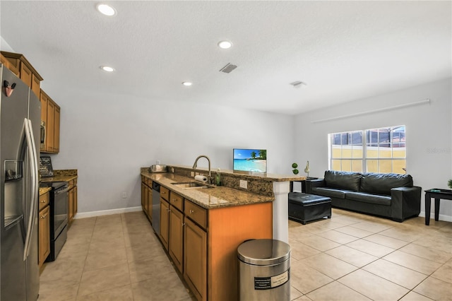 kitchen with kitchen peninsula, light tile flooring, dark stone countertops, sink, and appliances with stainless steel finishes