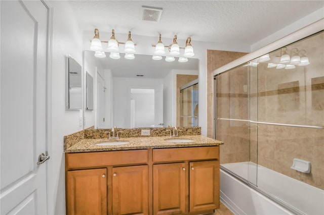 bathroom featuring enclosed tub / shower combo, a textured ceiling, and double sink vanity