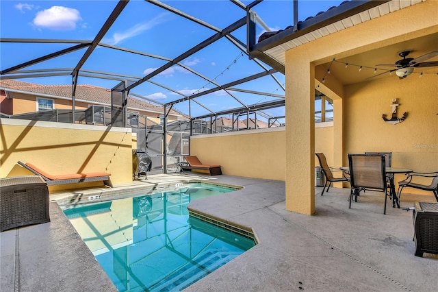 view of swimming pool featuring ceiling fan, glass enclosure, and a patio