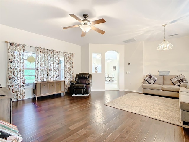 living room with dark wood-type flooring and ceiling fan with notable chandelier