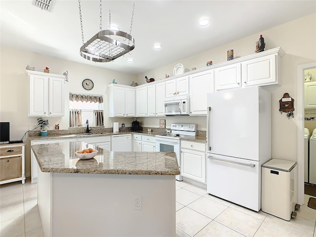 kitchen with light stone countertops, white appliances, white cabinetry, and washer and clothes dryer