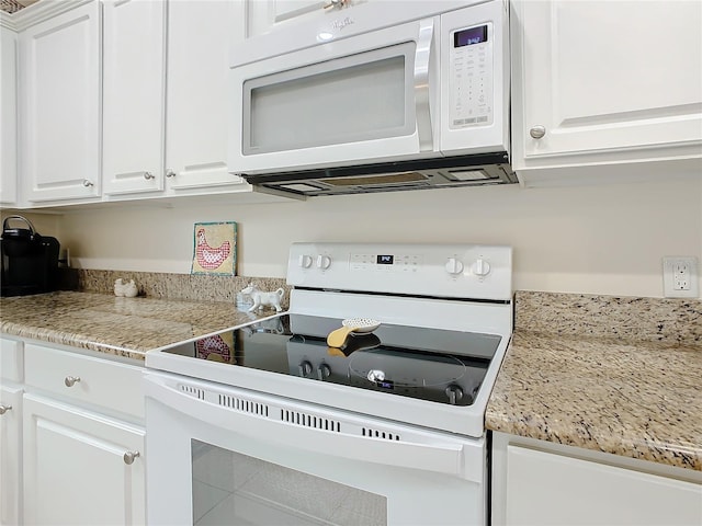 kitchen featuring light stone countertops, white appliances, and white cabinetry