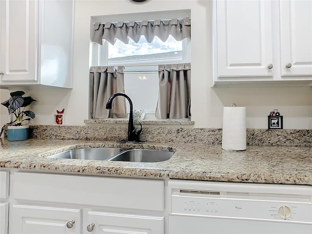 kitchen featuring white cabinets, white dishwasher, light stone counters, and sink