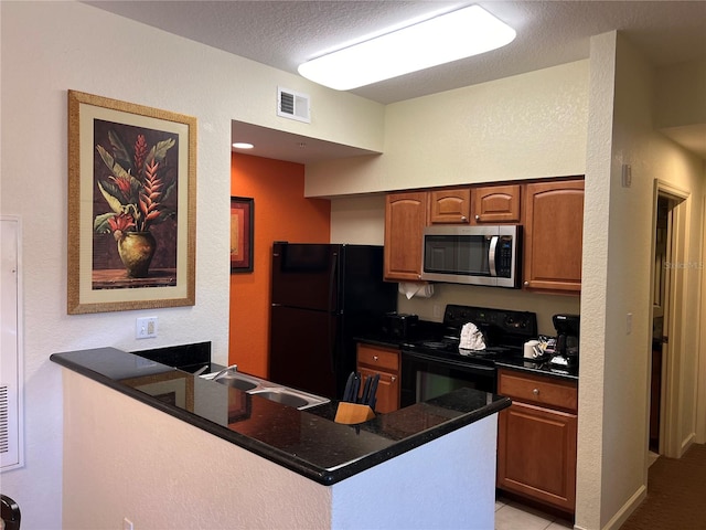 kitchen featuring dark stone counters, a textured ceiling, kitchen peninsula, black appliances, and sink