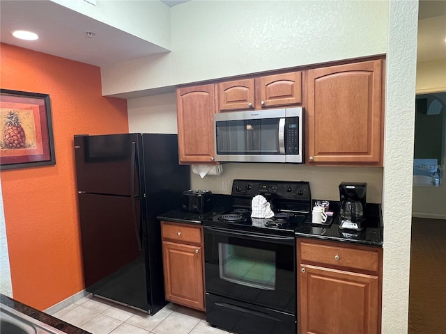 kitchen featuring dark stone counters, light tile floors, and black appliances