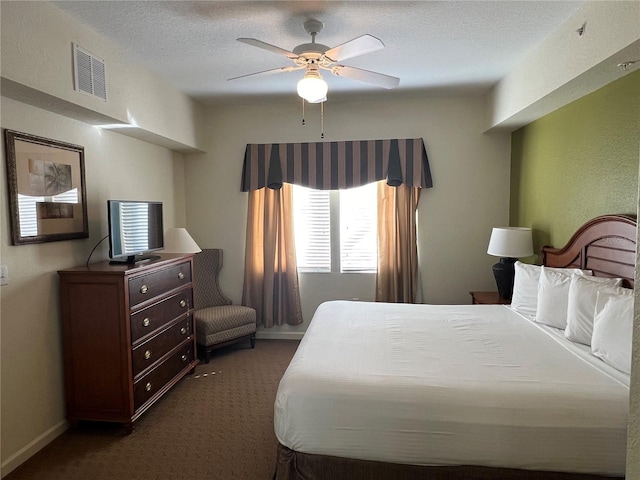 bedroom with dark carpet, ceiling fan, and a textured ceiling