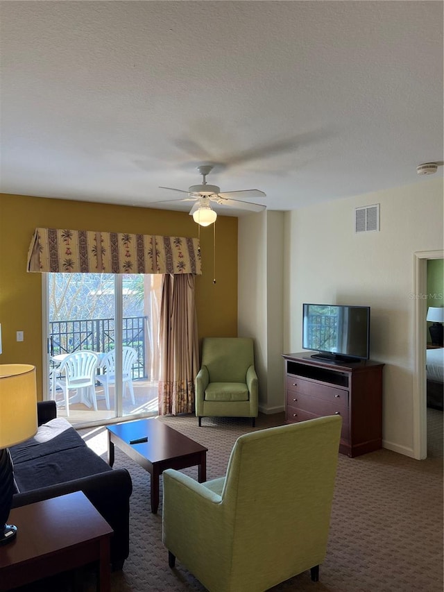 living room with carpet flooring, a textured ceiling, and ceiling fan