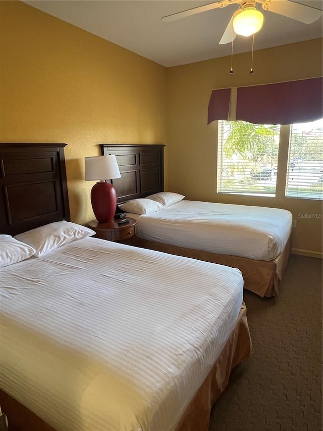 bedroom featuring dark colored carpet, multiple windows, and ceiling fan