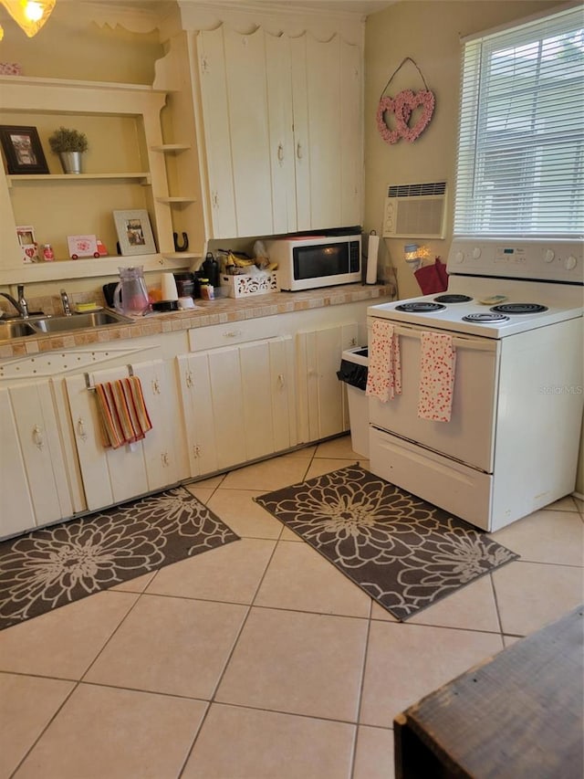 kitchen featuring a wall mounted AC, sink, light tile floors, white range with electric cooktop, and tile countertops