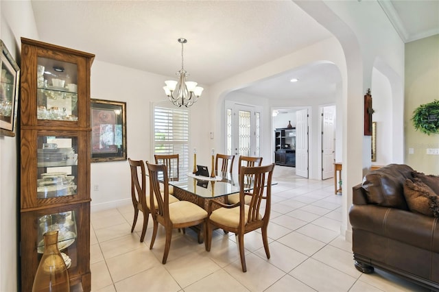 dining area with light tile flooring, crown molding, and an inviting chandelier