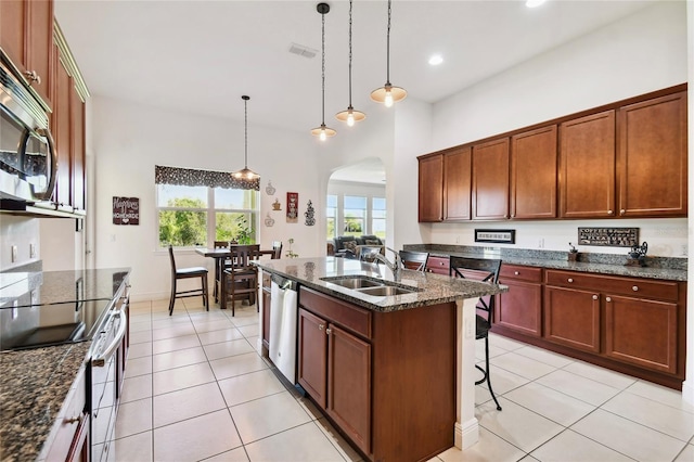 kitchen with light tile floors, a kitchen bar, appliances with stainless steel finishes, hanging light fixtures, and sink