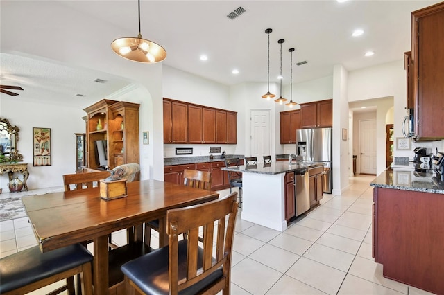 kitchen with a center island, dark stone counters, ceiling fan, and pendant lighting