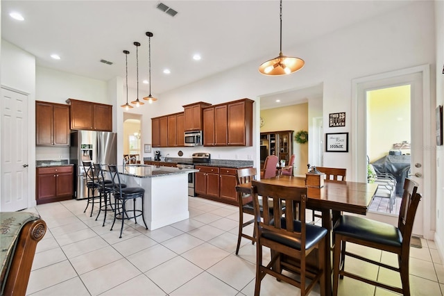 kitchen with light tile flooring, pendant lighting, a center island, and appliances with stainless steel finishes