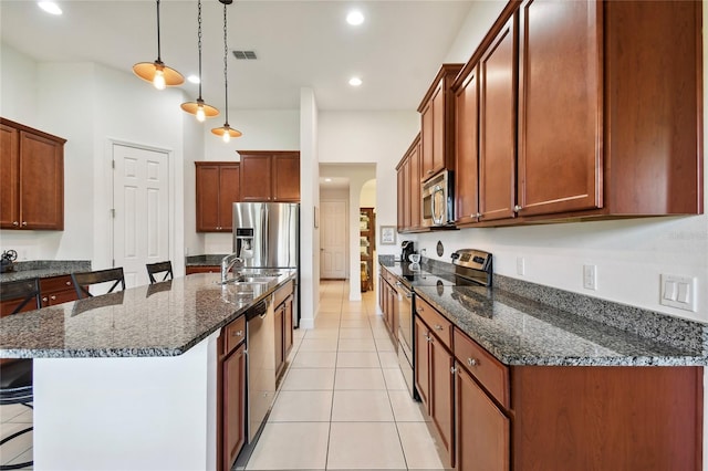 kitchen featuring pendant lighting, light tile floors, a breakfast bar, a center island with sink, and stainless steel appliances