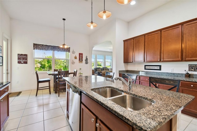 kitchen with a kitchen island with sink, decorative light fixtures, light tile floors, and dishwasher