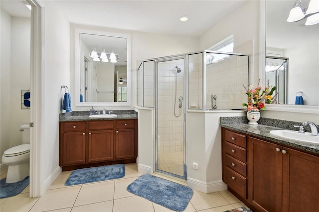 bathroom featuring a shower with door, tile floors, vanity with extensive cabinet space, and toilet