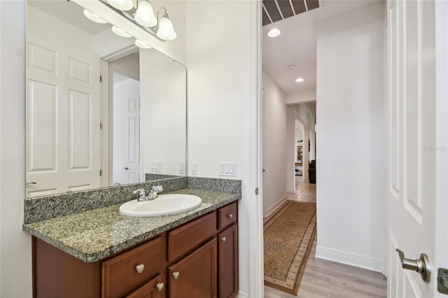 bathroom with hardwood / wood-style floors and vanity with extensive cabinet space